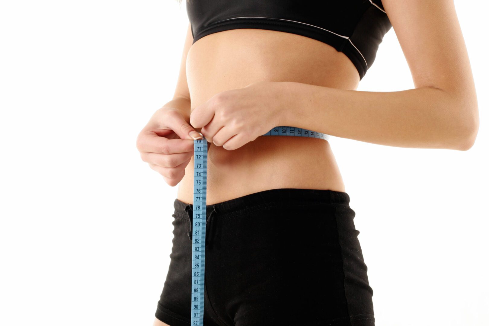 Young woman in black underwear measuring her waist with blue tape measure