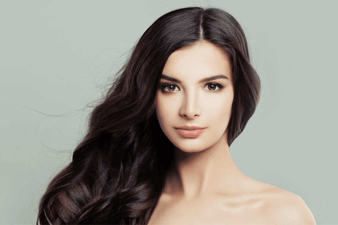 Young woman with beautiful face and black hair, isolated in gray background