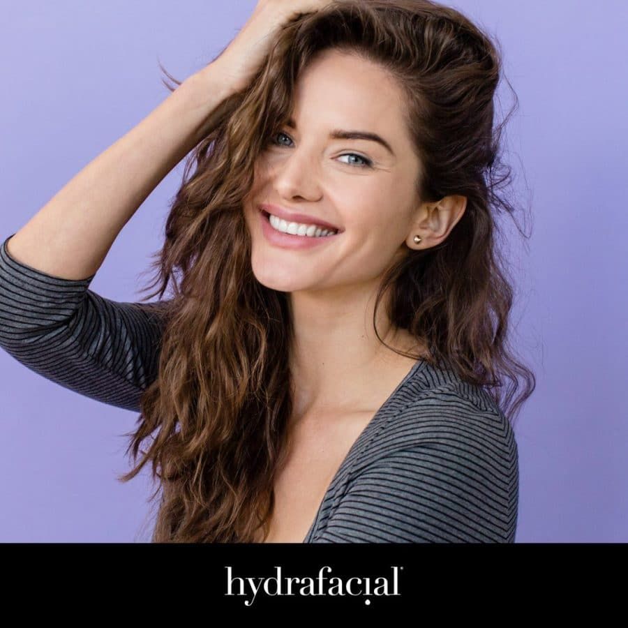 Portrait of a woman with her hands fixing her hair, used in a Hydrafacial poster