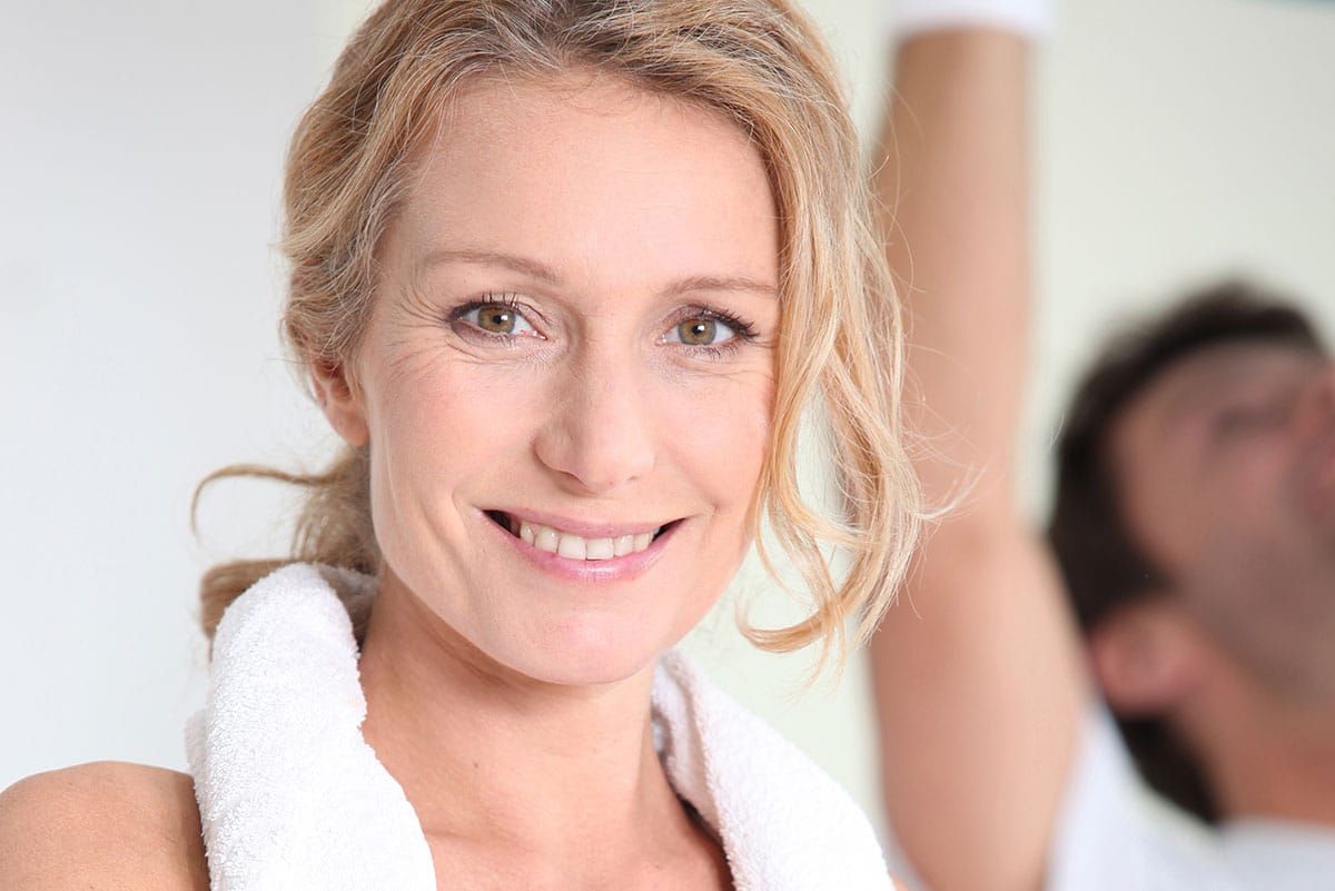 Post workout photo of a middle age woman with towel in her neck