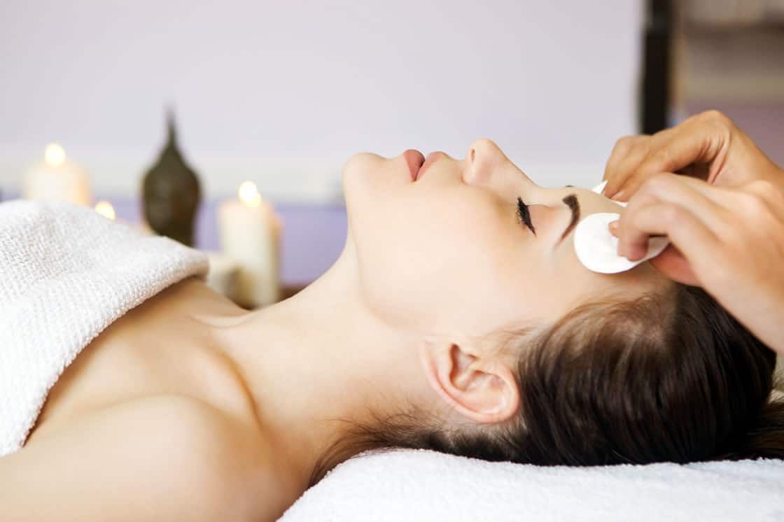 Female patient undergoing facial skin care, the aesthetician's hand is also framed in the photo