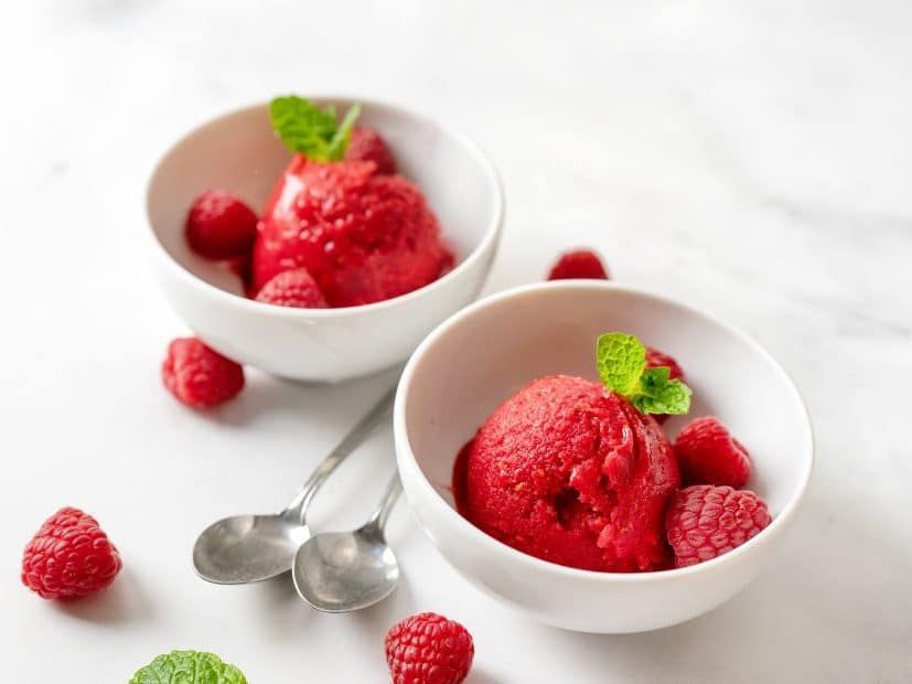 Two cups of raspberry sorbet with spoons