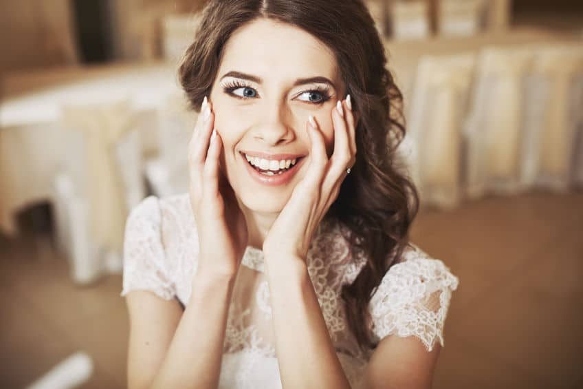 Young woman wearing white lace blouse touching her face with two hands