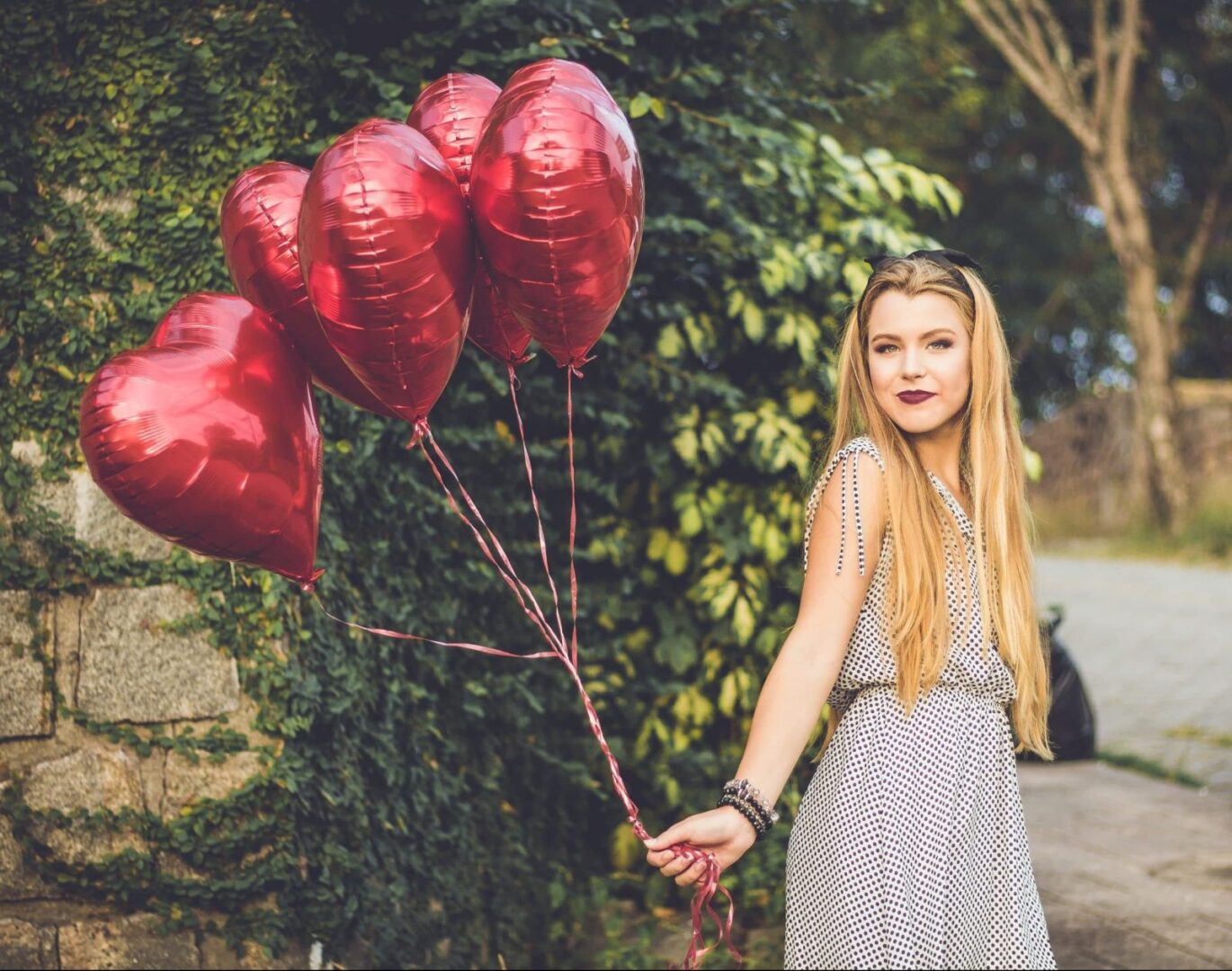 Young lady with blonde hair holding heart-shaped baloons