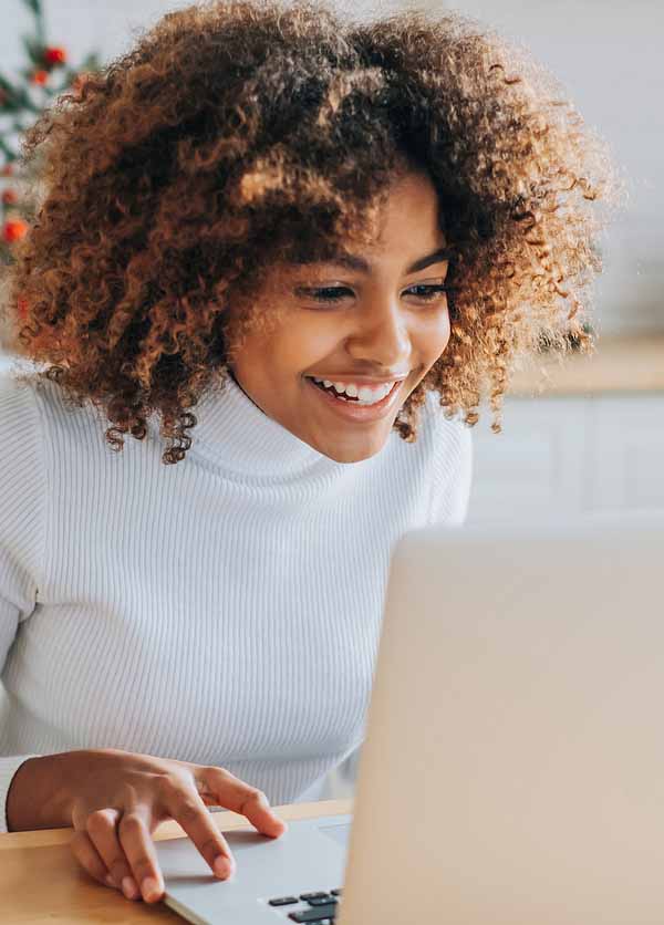 Dark skinned girl looks in laptop and enjoys online shopping