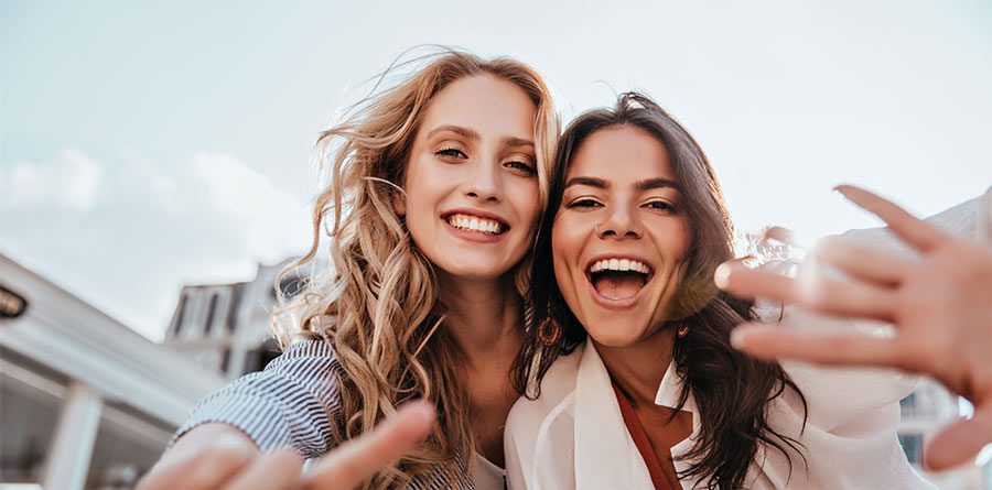 Lovable caucasian girls expressing positive emotions to camera. Outdoor photo of refined sisters posing on sky background.