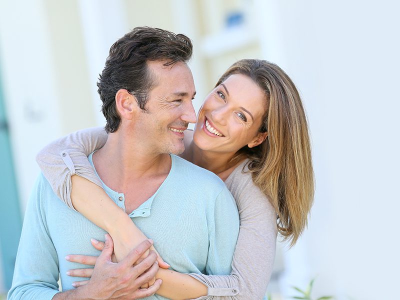Middle-aged couple embracing in front of house